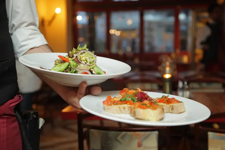 Ospătar care servește două farfurii într-un restaurant